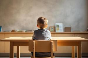 A young boy seen from behind, sitting attentively at a classroom desk, highlights the quiet focus and learning environment of a modern school setting. Copy space for text. photo
