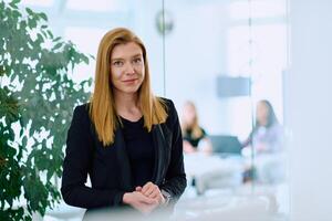 Portrait of a Blonde Businesswoman in a Modern Office with Her Workspace and Colleagues in the Background. photo