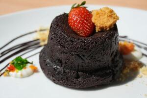 Delicious chocolate fondant or lava cake with cream, strawberry, and cake biscuit crumbles, Hot chocolate dessert pudding with liquid chocolate center, fondant au chocolate photo
