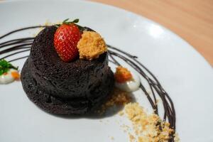 Delicious chocolate fondant or lava cake with cream, strawberry, and cake biscuit crumbles, Hot chocolate dessert pudding with liquid chocolate center, fondant au chocolate photo