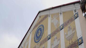 Old white and yellow building. ACTION. The front of a yellow house with white stripes. Old patterns of birds and flowers on the facade of the building video