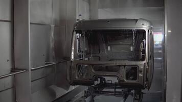 Robots at the factory paint the cab of the car. SCENE. At the factory, a white car is painted by robotic hands. On the assembly line, the car is painted in a light color. The car body is painted on video