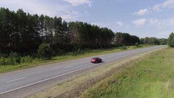 Top view of passing car on highway in forest. Scene. Beautiful view of country road with forest on sunny day. Trip out of town video