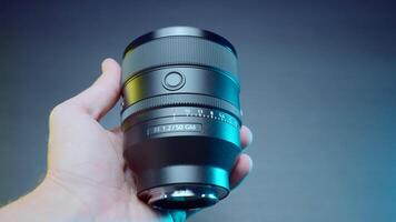 Russia, Moscow - June 3, 2022. New photo lens in hand. Action. Close-up of new lens for professional camera. New generation lens in photographer's hand video