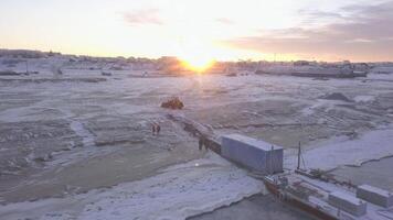 Snowy mountains .Clip.An empty area with snow on which construction is taking place and there are large loaded ships parked on the shore and the bright sun is shining. video