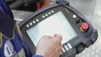 AUSTRIA, VIENNA - MARCH 27, 2022. An employee is typing something on a working tablet. SCENE. At the factory, the engineer selects the values on the work tablet. The worker runs his hand over the video