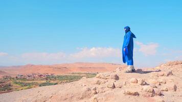 Man on background of oasis. Action. Man in Arab suit stands over oasis in desert. Beautiful man in desert on background of oasis video