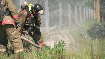 Firefighters. Clip. Two masked men who conduct exercises with a hose and water with special equipment and in a special uniform. video