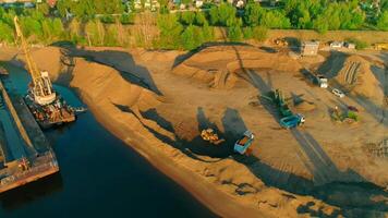 Drone flight over the sand and gravel mining on a sunny summer day near the river. Scene. Concept of heavy industry and machinery. video