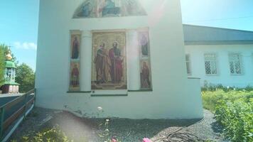 The temple is made of white stone.Clip.The park next to which there is a white church with a large icon on the wall . video