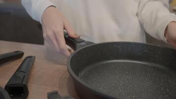The cook collects pots. Action. A man in a white coat stands and puts one frying pan into another and collects. video