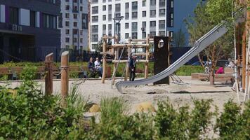 Modern playground with plants. Stock footage. Children play on modern playground. Residential complex with temporary landscape and playgrounds in summer video