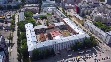 View from a helicopter.Clip.A view of a small summer town with small 5-storey houses ,a large building on the square and various parks nearby and walking people. video