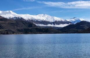 The mountain snow on top behind the lake photo