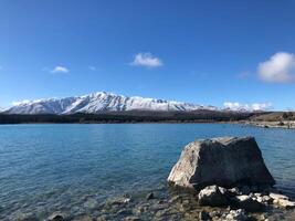 The rock in the lake and snow mountain background. photo