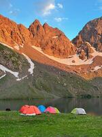 Camping tent by the lake in front of the mountain. photo