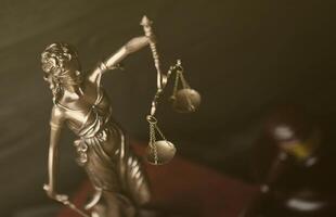 The Statue of Justice - lady justice or justitia the Roman goddess of Justice. Statue on brown book with judge gavel. Concept of judicial trial, courtroom process and lawyers work photo