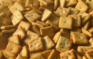 Background texture of small edible squares baked from dough and sprinkled with salt. A lot of salt cracker photo