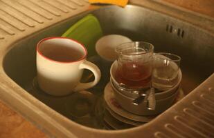 Stack of dirty dishes with food leftovers in the kitchen sink. Unwashed dishes photo