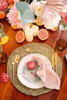 Name card lies on a plate next to a knotted napkin on a festive table with a colorful bouquet of flowers photo