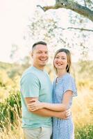 Smiling man and woman hugging while standing in a park photo