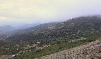 Morning view from the Dragobrat mountain peaks in Carpathian mountains, Ukraine. Cloudy and foggy landscape around Drahobrat Peaks photo