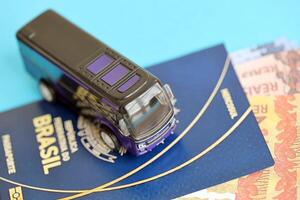 Blue Brazilian passport with money and small bus on blue background close up photo