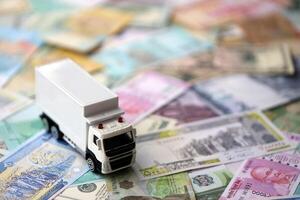 Delivery truck on many banknotes of different currency. Background of trucking or moving concept photo