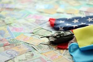 Toy tank on US flag and ukrainian flag on many banknotes of different currency photo