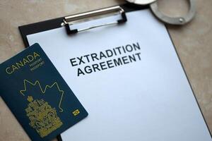 Passport of Canada and Extradition Agreement with handcuffs on table photo