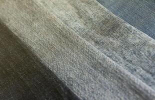 Detailed abstract texture of dark blue denim cloth. Background image of old used denim trousers fabric photo