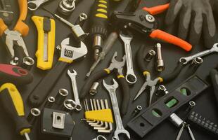 Handyman tool kit on black wooden table. Many wrenches and screwdrivers, pilers and other tools for any types of repair or construction works. Repairman tools photo