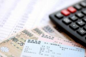 Light blue and red Japan Health Insurance cards on table with japanese yen money and calculator photo
