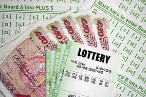 Green lottery tickets and Great Britain pounds money bills on blank with numbers for playing lottery photo