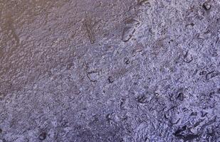 Close up of muddy puddle with small stones on wet surface. Background texture with top view photo