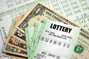 Green lottery tickets and US money bills on blank with numbers for playing lottery photo