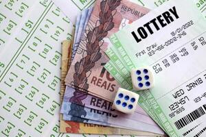 Green lottery tickets and brazilian reals money bills on blank with numbers for playing lottery photo