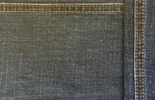 Detailed abstract texture of dark blue denim cloth. Background image of old used denim trousers fabric photo