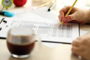 Female student hands testing in exercise and taking fill in exam paper sheet with pencil at school test photo