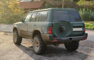 Automobile in a countryside landscape with a mud road. Off-road 4x4 suv automobile with ditry body after drive in muddy road photo
