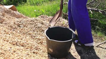 A man in overalls puts rubble from a pile into a bucket with a shovel for construction needs video