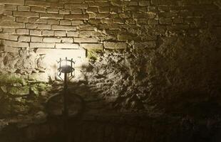 Lighted medieval castle torch hanging on a stone wall, vintage objects photo