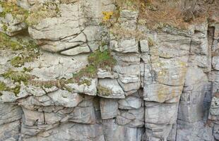 Light coarse natural rock stone background. Mining cliff rough front surface. Big limestone stack backdrop. Heavy grunge damaged granite block texture photo