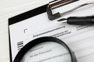 German annual income tax return declaration form blank on A4 tablet lies on office table with pen and magnifying glass photo