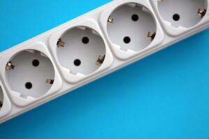 White electrical multi plug extender with european socket on bright blue background photo