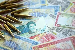 Many bullets and iranian rials money bills close up. Concept of terrorism funding or financial operations to support war photo