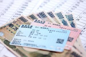 Light blue and red Japan Health Insurance cards on table with japanese yen money photo