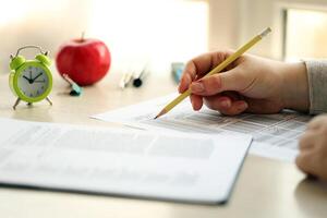 Female student hands testing in exercise and taking fill in exam paper sheet with pencil at school test photo