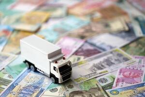Delivery truck on many banknotes of different currency. Background of trucking or moving concept photo
