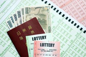 Lottery tickets lies with japanese yen bills on gambling sheets with numbers for marking to play lottery photo